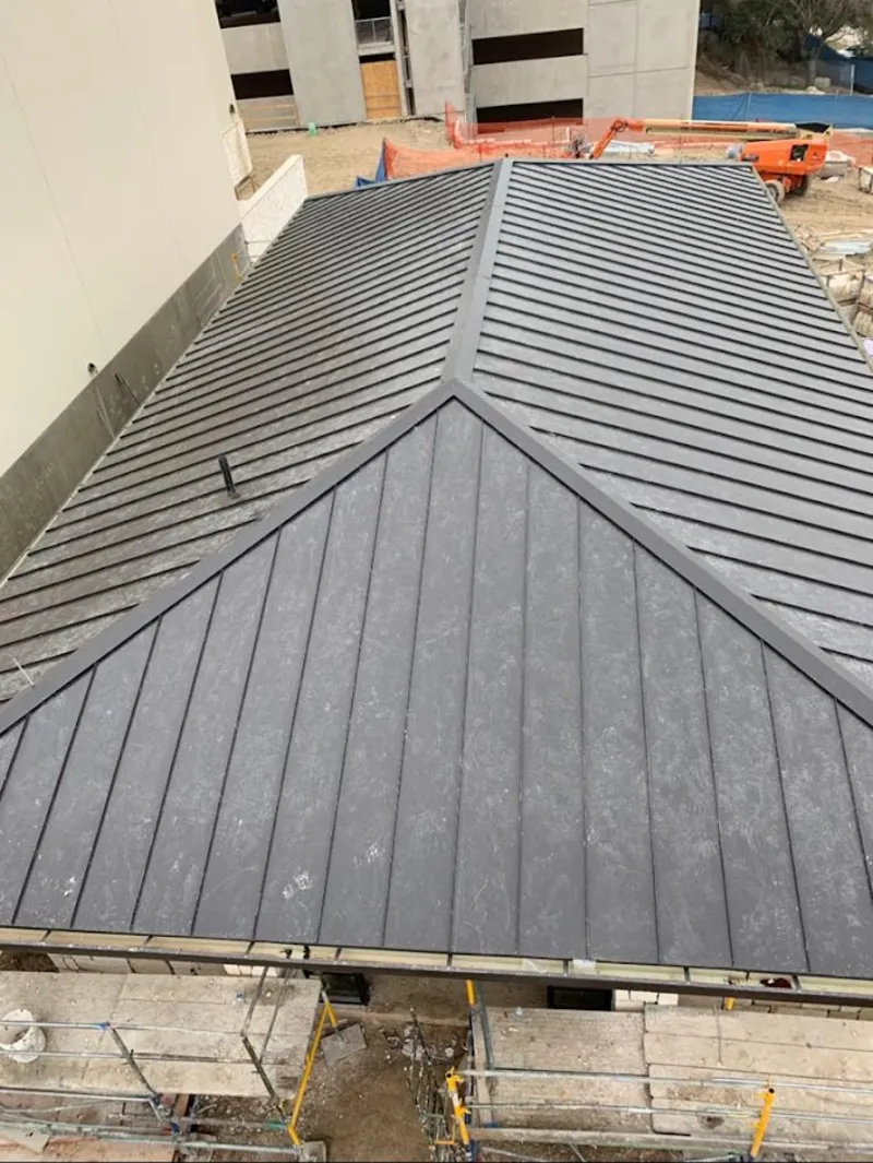 Commercial metal roof construction with crane equipment in Owasso